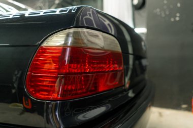 Otoparkta ya da araba servisinde temizlik yaptıktan sonra siyah bir arabanın arka lambasını ve tamponunu yakın plan çek.