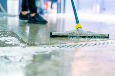 Bir oto yıkama işçisinin araba yıkama kutusundaki su ve köpüğü temizlerken çekilmiş yakın plan fotoğrafı.