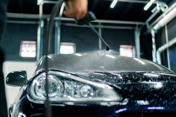 Zbliżenie Przedniego Reflektora Czarnego Samochodu Podczas Stosowania Myjni Samochodowej Butelki — Zdjęcie stockowe