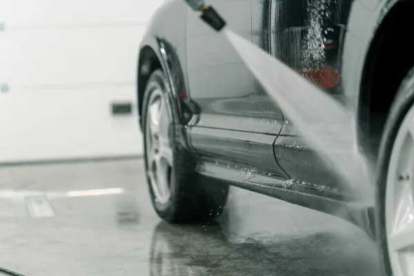 Zbliżenie Pracownika Myjni Samochodowej Myjącego Parapety Obręczach Czarnego Luksusowego Samochodu — Zdjęcie stockowe