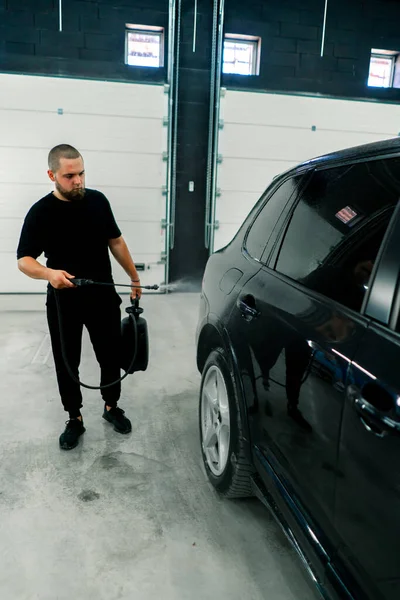 Egy Férfi Autómosó Alkalmazott Autómosót Használ Egy Fekete Luxusautóra Szórópisztollyal — Stock Fotó