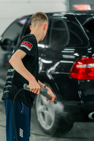 Muž Mytí Aut Zaměstnanec Myje Černé Luxusní Auto Vysokotlakou Myčkou — Stock fotografie