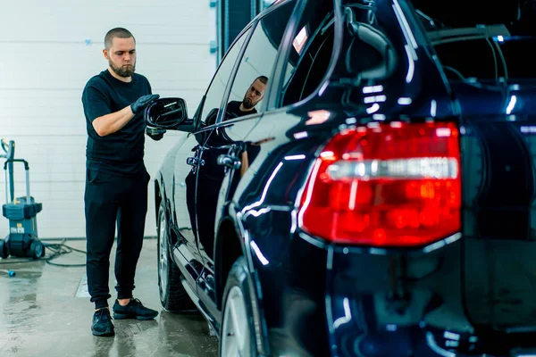 黒い手袋に焦点を当てた男性用洗車労働者は スポンジカーケアのコンセプトを使用して高級ブルーカーの鏡を磨きます — ストック写真