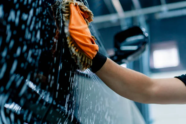 洗車シャンプー付きブラックラグジュアリーカーを洗浄するマイクロファイバー布を使用した洗車作業員のクローズアップ — ストック写真
