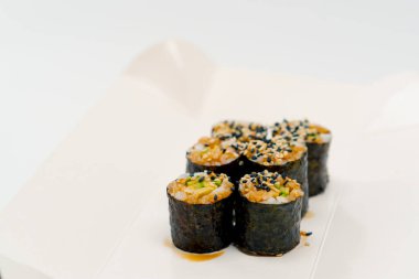 Beyaz arka planda suşi teslimat kutusunda soya soslu avokado ile maki rulosunun yakın plan çekimi.