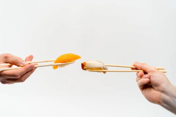 白い背景にウナギ寿司とサーモン寿司を空中に保持する箸で男性の手のクローズアップ — ストック写真