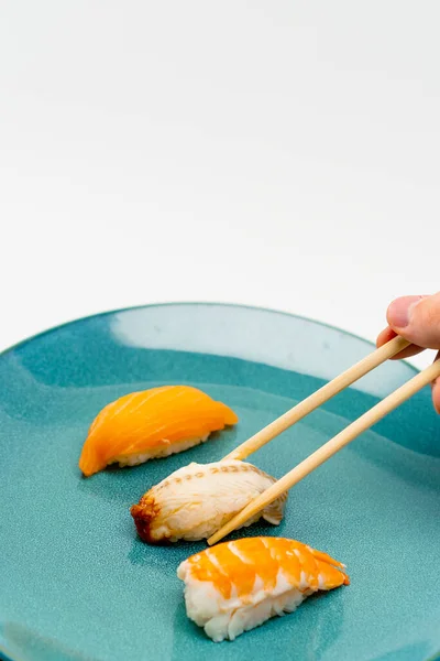 箸を使って男性の手を閉じ サーモンとエビの寿司を白い背景に一枚のウナギの寿司を取る — ストック写真