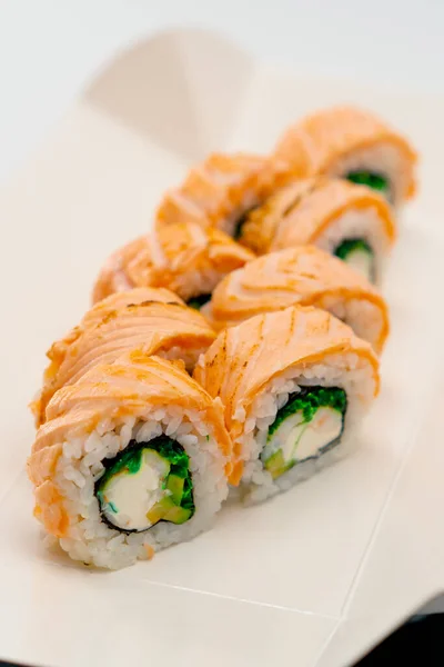 在寿司盒里的白色背景上 用鲑鱼黄瓜和奶酪制作的菲拉迪面包卷的特写 — 图库照片