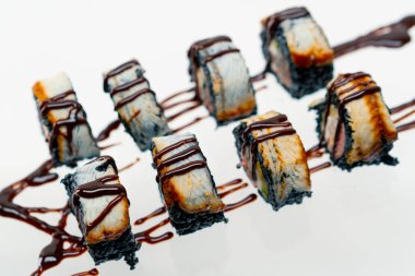 Kaliforniya dürümlerine yakın çekim, üzerinde unagi sosu serpiştirilmiş siyah pirinç yılan balığı, güzel mavi tabakta suşi ve Asya mutfağı aşkı kavramı.