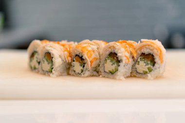 Beyaz mutfak tahtasındaki salatalık peyniri ve karidesli California dürümünün yakın çekimi.