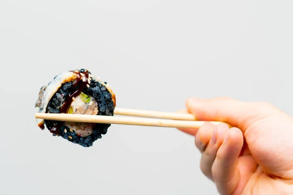 Close Sushi California Black Rice Eel Man Holds Chopsticks White — Stock Photo, Image