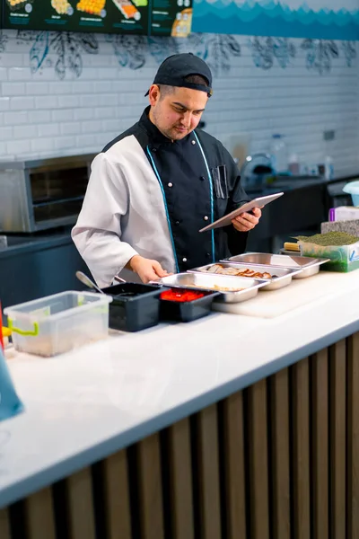 Gedachte Sushi Chef Met Tablet Zijn Handen Bij Keukentafel Waarop — Stockfoto