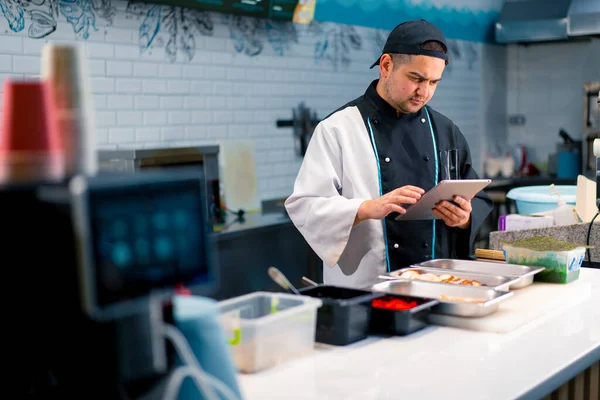 Chef Sushi Pensativo Com Tablet Suas Mãos Perto Mesa Cozinha — Fotografia de Stock