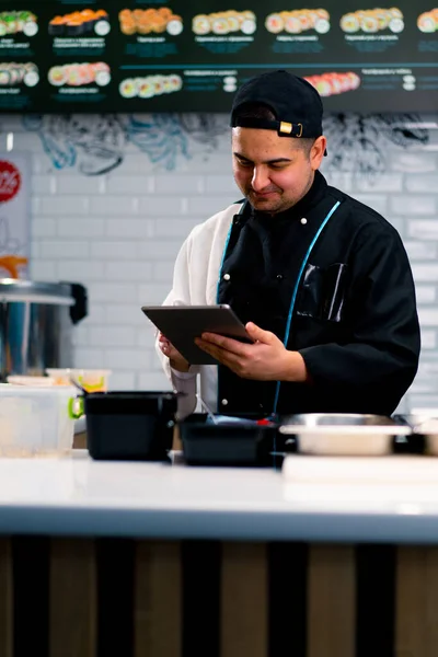 Chef Sushi Pensativo Com Tablet Suas Mãos Perto Mesa Cozinha — Fotografia de Stock