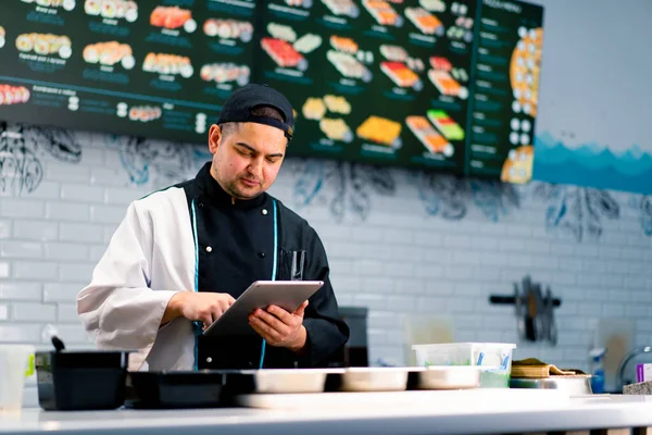Chef Sushi Reflexivo Con Tableta Las Manos Cerca Mesa Cocina — Foto de Stock