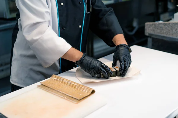 Een Sushi Chef Kok Draagt Zwarte Handschoenen Een Pet Snijdt — Stockfoto