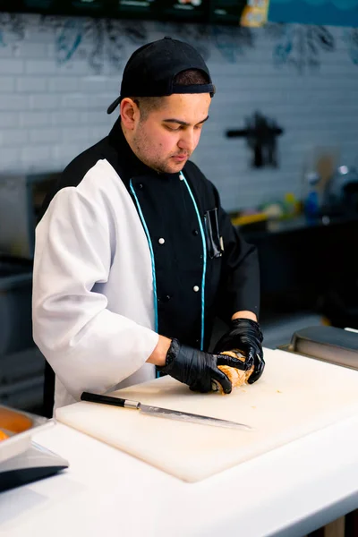 ホワイトキッチンボードにシードサーモンクリームチーズとキュウリのフィラデルフィアロールを準備する過程でシェフ — ストック写真