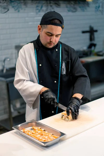 Zbliżenie Sushi Człowiek Czarny Rękawiczki Cięcie California Rolka Biały Kuchnia — Zdjęcie stockowe
