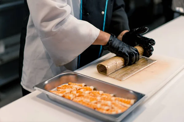 在厨房桌上用米片 鲑鱼片 凝乳芝士黄瓜鳄梨制作寿司的黑手套寿司制造商特写镜头 — 图库照片