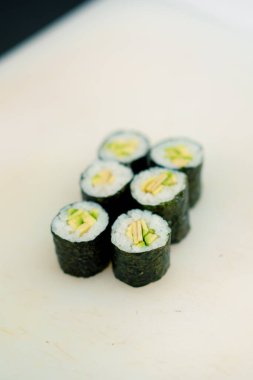 Suşi restoranının mutfağındaki mutfak masasında avokado soslu maki rulolarının yakın çekimi.