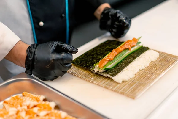 Närbild Sushi Maker Svarta Handskar Förbereda Sushi Med Ris Nori — Stockfoto