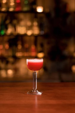 Kulüpteki barda barın üstünde cin ve yumurta beyazı olan kırmızı bir Clover Club kokteyli.