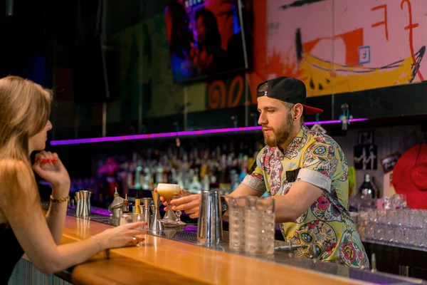 プロの若いバーテンダーは バーのクラブでガールズクライアントに美味しいアルコールカクテルを与えます — ストック写真