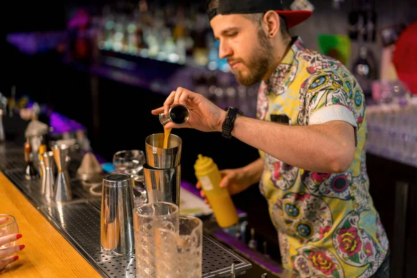 専門の若いバーテンダーは バーでクラブでカクテルを作るシェーカープロセスに測定カップからアルコールを飲む — ストック写真