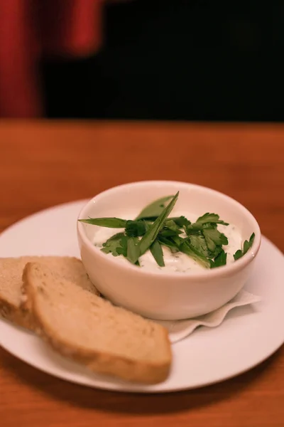クラブバーのテーブルに白いソースとグリーンとパンクロタンが付いたホワイトプレートのクローズアップ — ストック写真