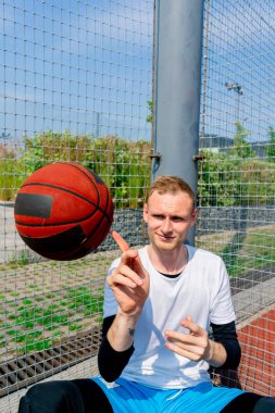 Basketbol oyuncusu, basketbol serbest stil becerilerini göstermek için parmağında basketbol topunu döndürüyor.