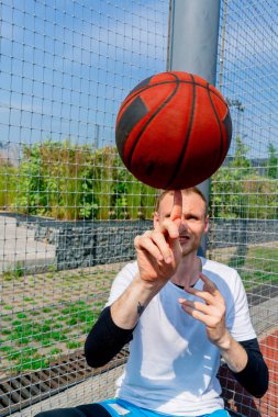 Basketbol oyuncusu, basketbol serbest stil becerilerini göstermek için parmağında basketbol topunu döndürüyor.