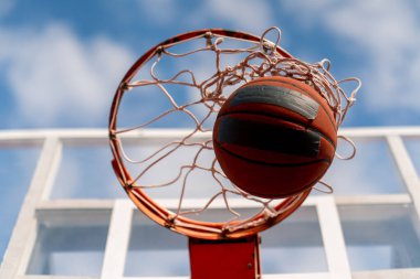 Basketbol topunun, basketbol ve spor yapma sevgisi konseptine vurduğu yakın çekim bir basketbol potası.