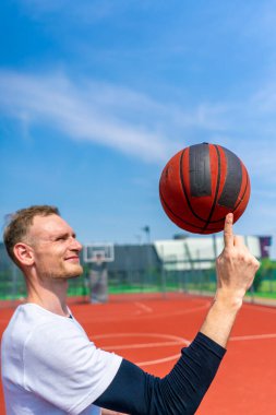 Basketbol oyuncusu, basketbol serbest stil becerilerini göstermek için parmağında basketbol topunu döndürüyor.