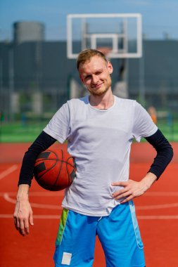 Park 'taki bir basketbol sahasında elinde top tutan uzun boylu bir basketbolcunun portresi.