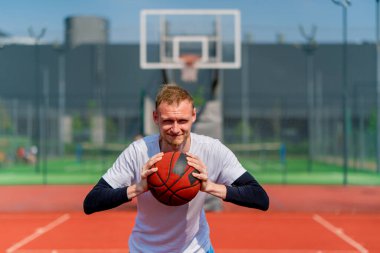 Park 'taki bir basketbol sahasında elinde top tutan uzun boylu bir basketbolcunun portresi.