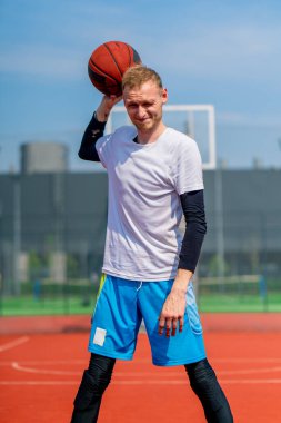 Park 'taki bir basketbol sahasında elinde top tutan uzun boylu bir basketbolcunun portresi.