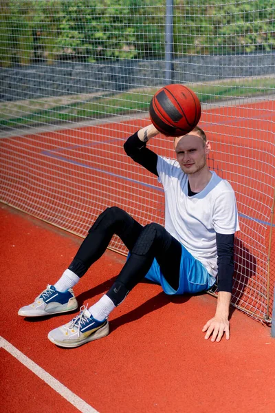 Ένας Ψηλός Μπασκετμπολίστας Μια Μπάλα Στο Χέρι Κάθεται Στο Δίχτυ — Φωτογραφία Αρχείου