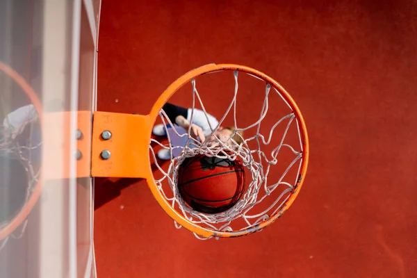 Close-up of basketball ring into which a tall guy basketball player throws the ball from below the concept of admiring the game of basketball