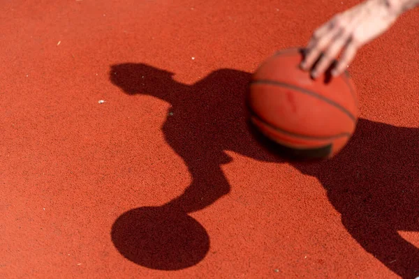 バスケットボールの男の影がボールをドリブルしながらバスケットボールコートの床に閉じ込められる — ストック写真