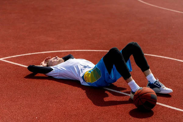 Высокий Парень Баскетболист Лежит Баскетбольной Площадке Парке Вместе Баскетбольным Отдыхом — стоковое фото