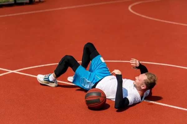 Vysoký Chlap Basketbalista Ležící Basketbalovém Hřišti Parku Spolu Basketbalovým Odpočinkem — Stock fotografie