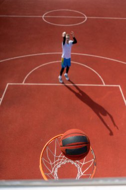 Basketbol ringine yakın çekimde uzun boylu bir basketbolcu topu fırlattı. Basketbol maçına hayran olma kavramı.