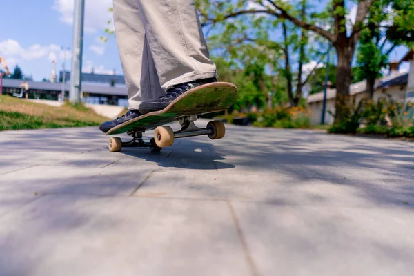 木の背景に対する都市公園のパス上のスケートボードトリックを行う若い男の子のクローズアップ — ストック写真