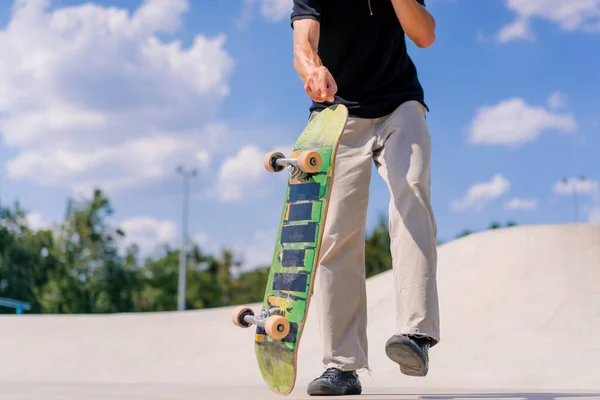 クローズアップ若いスケートボーダーの男は彼の手でスケートボードを投げ 都市のスケートパークでスタントを行うしようとします — ストック写真