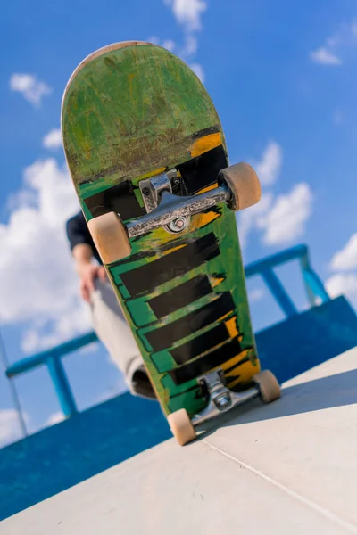スケートパークの若いスケートボーダーの足で保持されているスケートボードのクローズアップ — ストック写真
