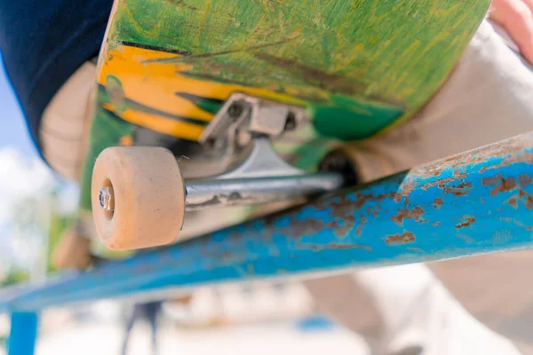 在城市的滑板公园里 一个坐在滑板上靠在扶手栏杆上的小男孩滑板手的特写 — 图库照片