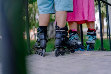 Randevudayken parkta paten kayan bir çiftin bacaklarına yakın çekim.