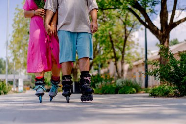 Genç çift yazın şehir parkında paten kayarken büyük beden mankenlerle çıkıyor.