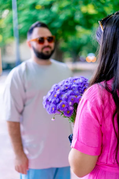 若いカップル男は公園の女の子に花束を与え 彼女はそれに満足しています — ストック写真
