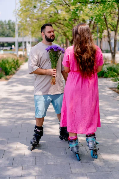 Young Couple Roller Skates Guy Gives Girl Bouquet Flowers Date — Stock Photo, Image